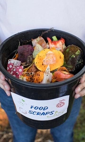 A person holding a bucket of food scraps