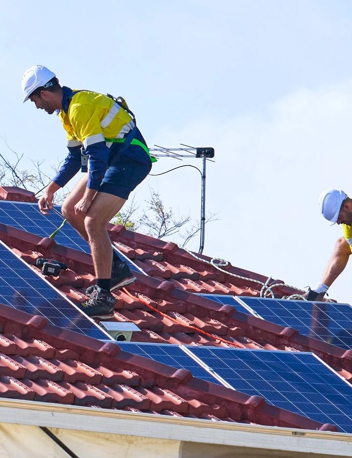 Two men on a roof install solar panels